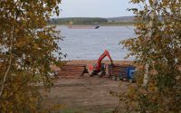a crane is working on a pile of logs