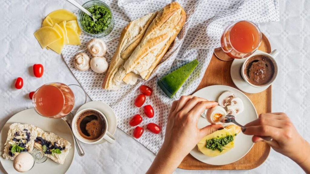 Overhead shot of a delicious breakfast flatlay featuring fresh ingredients and coffee on a white tablecloth.