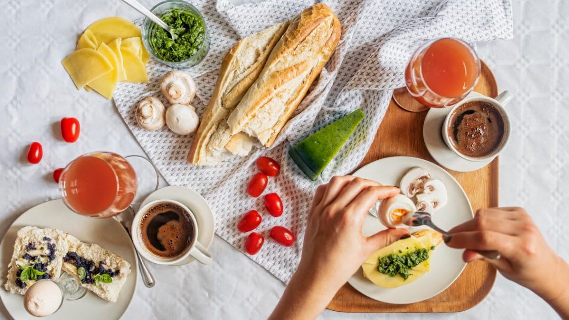 Overhead shot of a delicious breakfast flatlay featuring fresh ingredients and coffee on a white tablecloth.