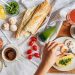 Overhead shot of a delicious breakfast flatlay featuring fresh ingredients and coffee on a white tablecloth.
