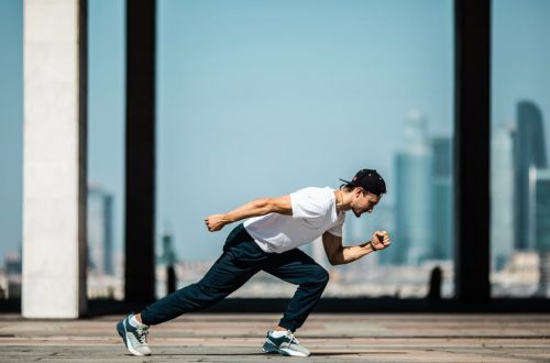 Dynamic shot of a young man sprinting outdoors in an urban setting with skyscrapers in the background.